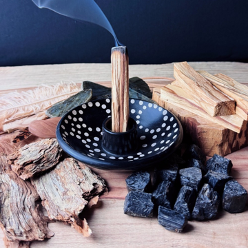 Handmade Black Ceramic Palo Santo Burner with inset white dot pattern on background with Palo Santo wood and resin